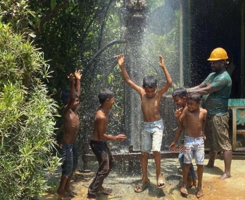 Des enfants se réjouissent sous un jet d’eau fraîche après le forage d’un puits par l’association Les P’tits Villages d’Afrique