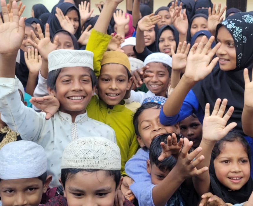 Groupe d’enfants souriants levant les mains lors d’une action éducative soutenue par l’association Les P’tits Villages d’Afrique