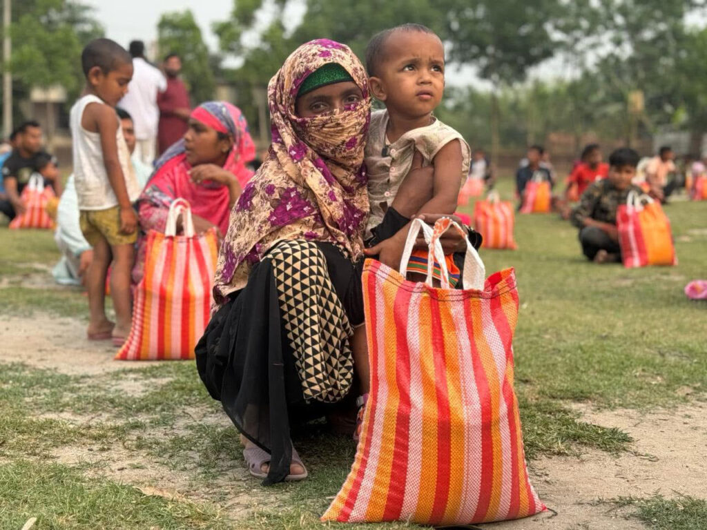 Offrir un colis alimentaire, 50€ pour sauver une famille de la faim 1 Offrir un colis alimentaire : Mère bangladaise tenant son enfant et recevant un colis alimentaire lors d'une distribution humanitaire des P'tits Villages d'Afrique