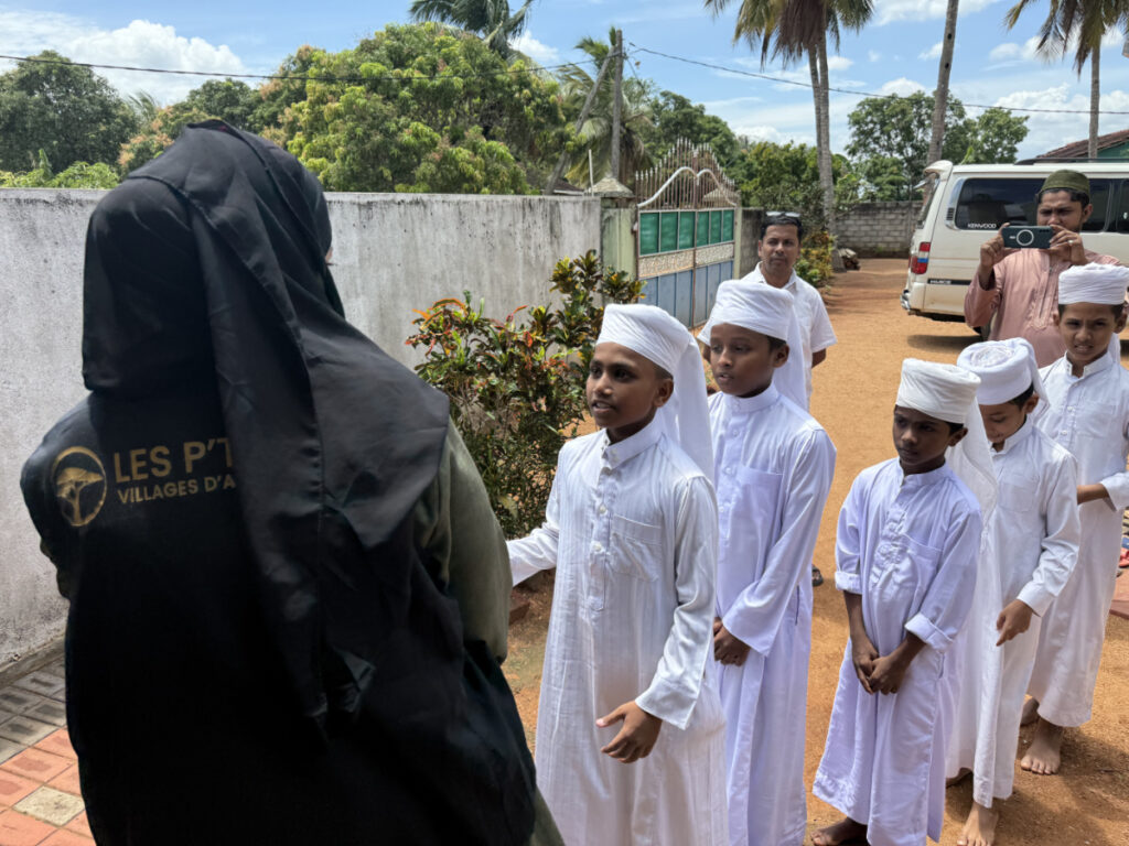 Offrir un Kit Scolaire, 30€ pour un changement essentiel 1 Offrir un kit scolaire : Bénévole de l'association Les P'tits Villages d'Afrique distribuant des kits scolaires aux enfants orphelins au Sri Lanka