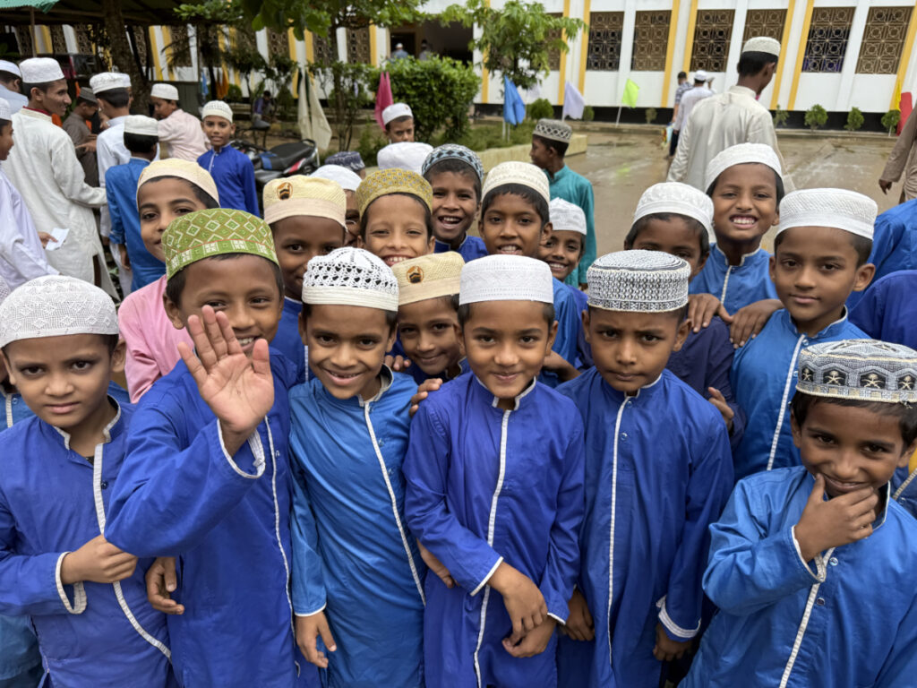 Groupe d’enfants souriants habillés en bleu, rassemblés à l’extérieur devant un orphelinat au Bangladesh.